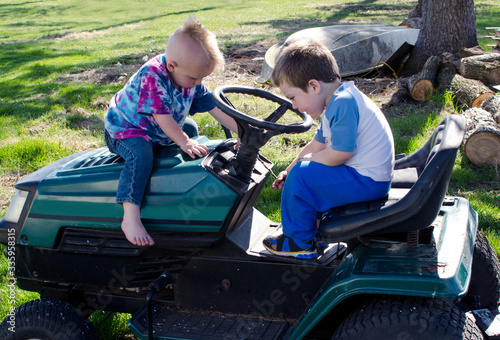 Two little boys are talking about this cool riding lawn mower, important boy talk for young future mechanics