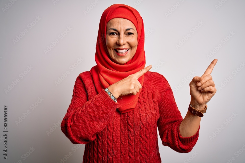 Middle age brunette woman wearing muslim traditional hijab over isolated white background smiling and looking at the camera pointing with two hands and fingers to the side. Middle age brunette woman wearing muslim traditional hijab over isolated white background smiling and looking at the camera pointing with two hands and fingers to the side.