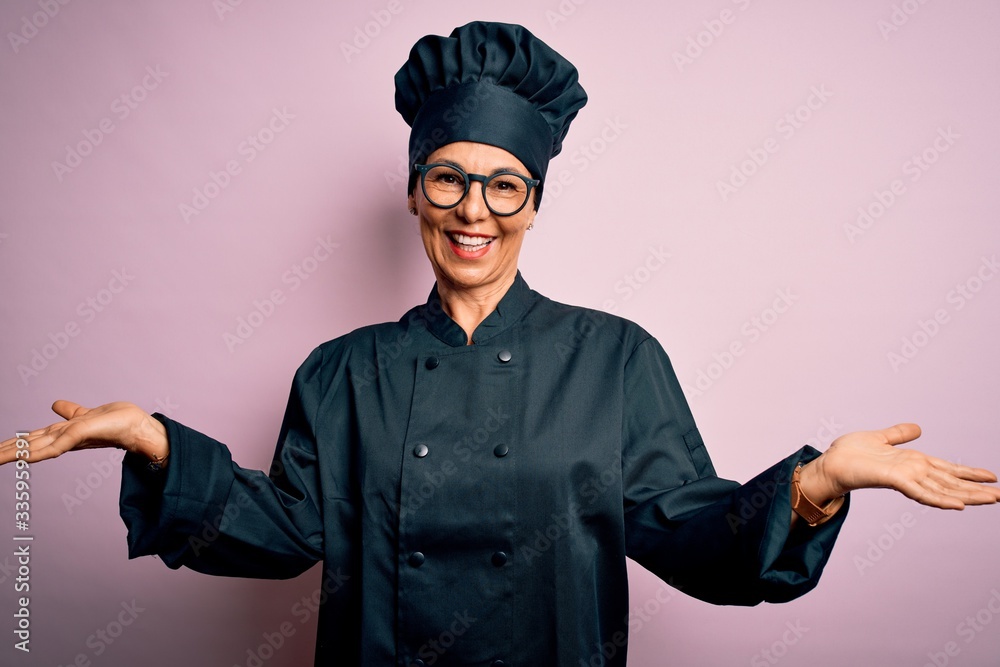 Middle age brunette chef woman wearing cooker uniform and hat over isolated pink background smiling showing both hands open palms, presenting and advertising comparison and balance