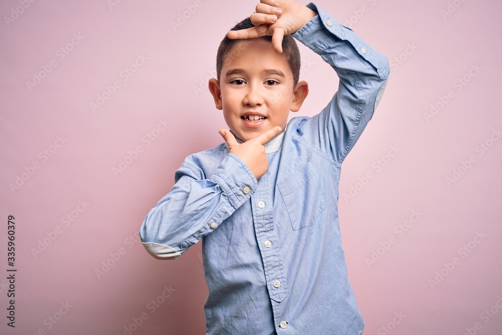 Young little boy kid wearing elegant shirt standing over pink isolated background smiling making frame with hands and fingers with happy face. Creativity and photography concept. Young little boy kid wearing elegant shirt standing over pink isolated background smiling making frame with hands and fingers with happy face. Creativity and photography concept.