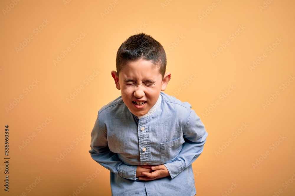 Φωτογραφία Young little boy kid wearing elegant shirt standing over yellow isolated background with hand on stomach because nausea, painful disease feeling unwell