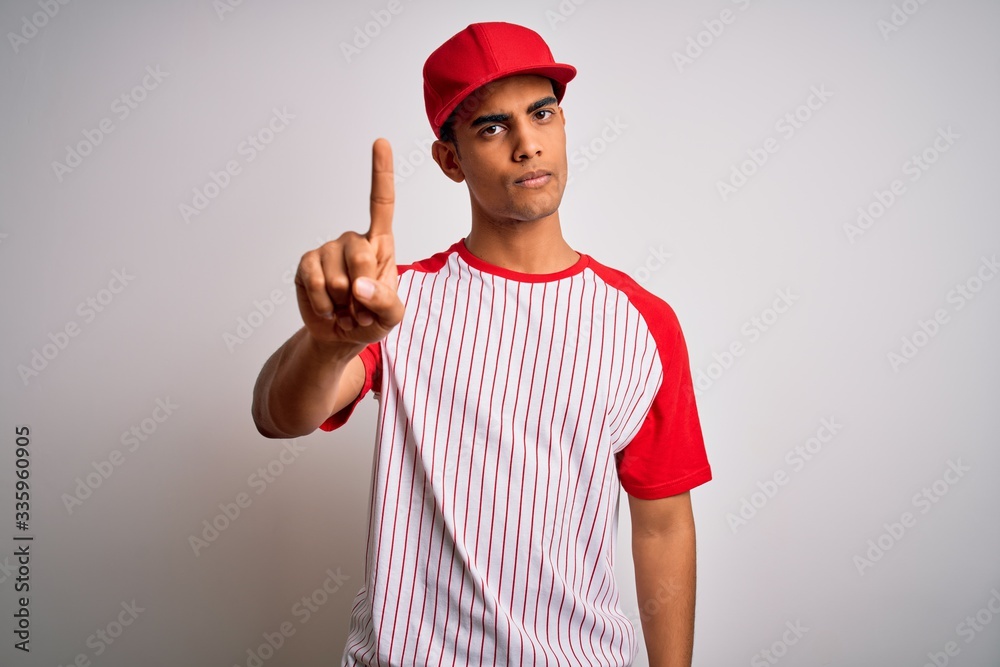 Young handsome african american sportsman wearing striped baseball t-shirt and cap Pointing with finger up and angry expression, showing no gesture Young handsome african american sportsman wearing striped baseball t-shirt and cap Pointing with finger up and angry expression, showing no gesture