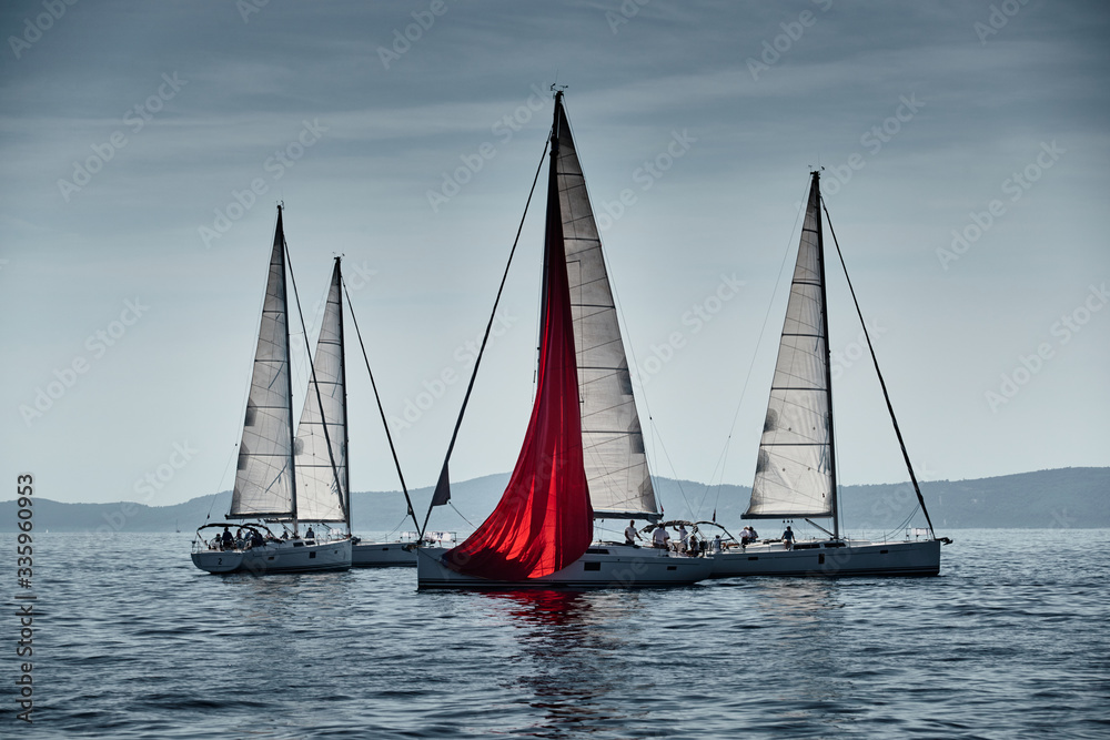 The race of sailboats, a regatta, reflection of sails on water, Intense competition, number of boat is on aft boats, bright colors, island with windmills are on background