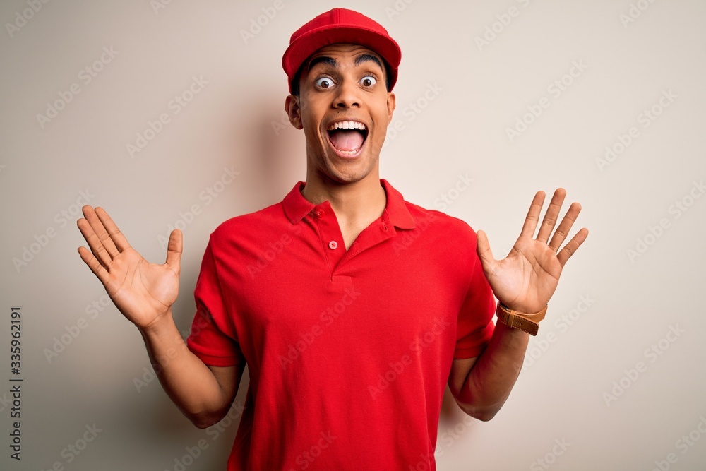 Young handsome african american man wearing casual polo and cap over red background celebrating crazy and amazed for success with arms raised and open eyes screaming excited. Winner concept Young handsome african american man wearing casual polo and cap over red background celebrating crazy and amazed for success with arms raised and open eyes screaming excited. Winner concept