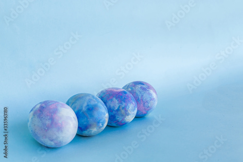 Four Space-colored Easter eggs on a trendy classic blue background. Easter card with a copy of the space for text. Minimal style.