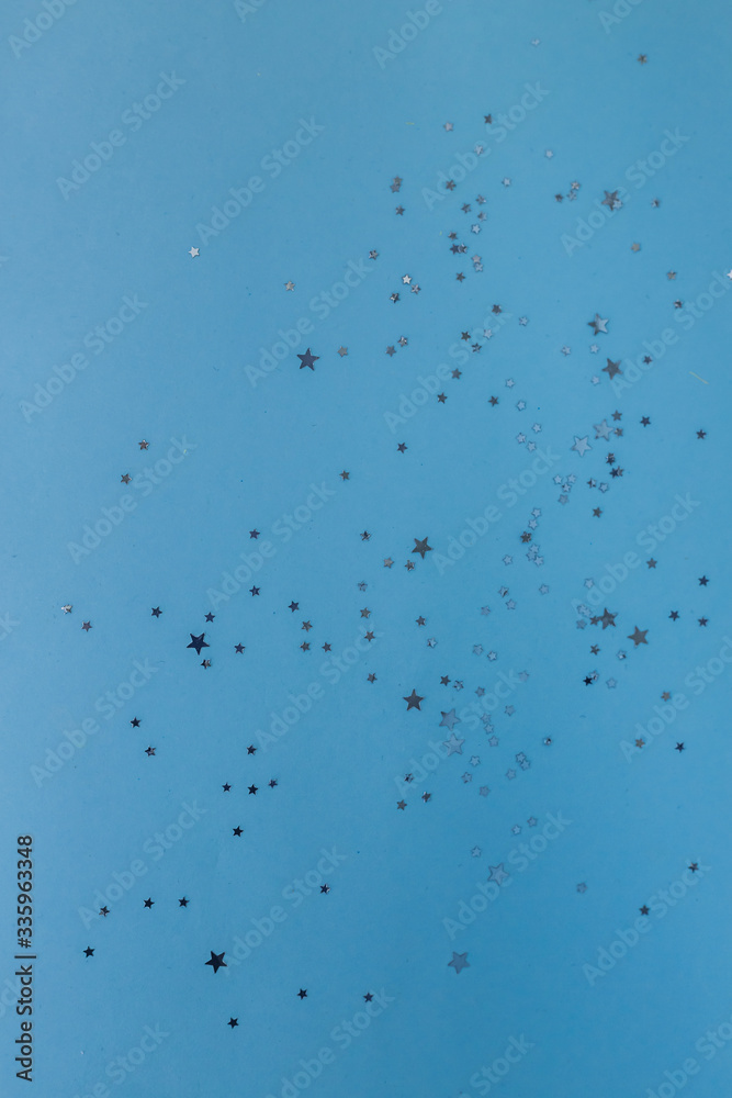 Star shaped silver sequins over classic blue background. Copy space.Holiday background for a greeting card. Top view, holiday concept. Star shaped silver sequins over classic blue background. Copy space.Holiday background for a greeting card. Top view, holiday concept.
