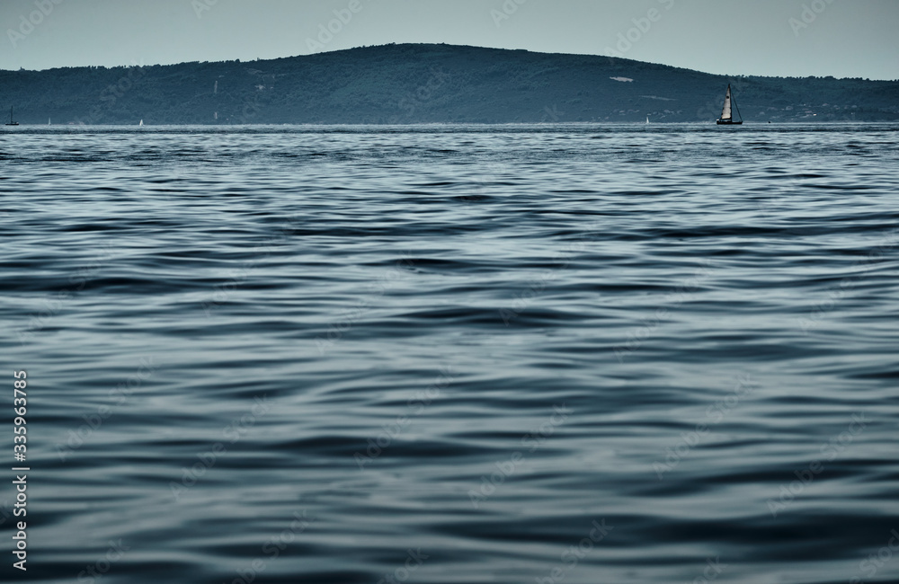 Fototapeta premium Beautiful sea landscape with lonely boat on the horizon, island is on background, bright colors