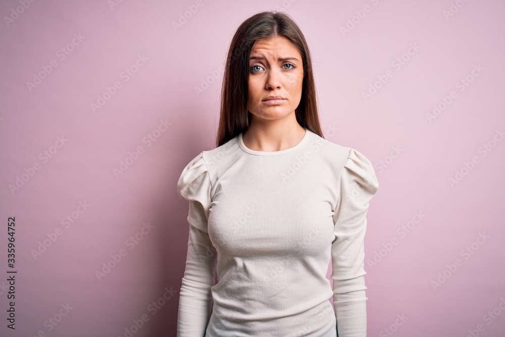 Young beautiful woman with blue eyes wearing casual white t-shirt over pink background skeptic and nervous, frowning upset because of problem. Negative person. Young beautiful woman with blue eyes wearing casual white t-shirt over pink background skeptic and nervous, frowning upset because of problem. Negative person.