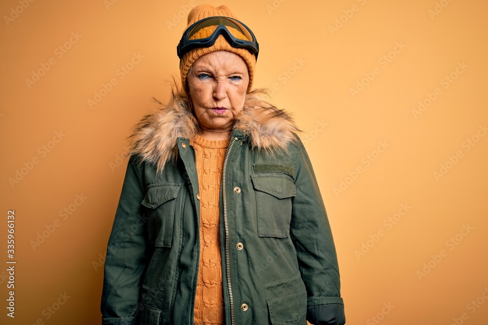 Senior beautiful grey-haired skier woman wearing snow sportswear and ski goggles skeptic and nervous, frowning upset because of problem. Negative person. Senior beautiful grey-haired skier woman wearing snow sportswear and ski goggles skeptic and nervous, frowning upset because of problem. Negative person.
