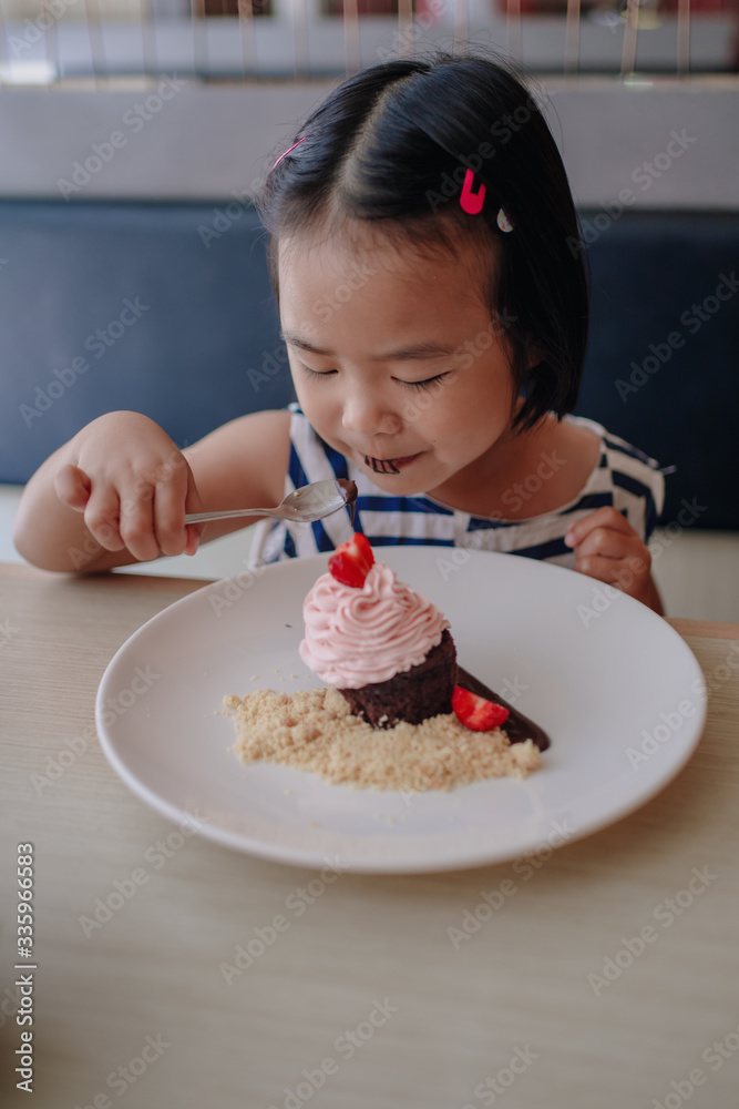 A girl eating happily with a strawberry whipped cream. 4 year old daughter Celebrating a birthday with a chocolate lava dessert