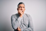 Middle age handsome grey-haired man wearing casual t-shirt over white background looking stressed and nervous with hands on mouth biting nails. Anxiety problem.