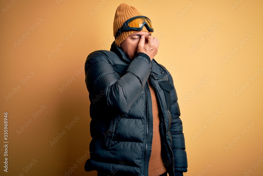 Middle age handsome grey-haired skier man on vacation wearing ski goggles tired rubbing nose and eyes feeling fatigue and headache. Stress and frustration concept. Middle age handsome grey-haired skier man on vacation wearing ski goggles tired rubbing nose and eyes feeling fatigue and headache. Stress and frustration concept.