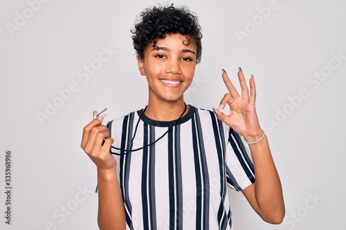 Obraz na plátne Young beautiful african american afro referee woman wearing striped uniform usin