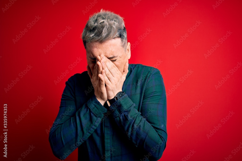 Young handsome modern man wearing elegant green shirt over red isolated background with sad expression covering face with hands while crying. Depression concept. Young handsome modern man wearing elegant green shirt over red isolated background with sad expression covering face with hands while crying. Depression concept.