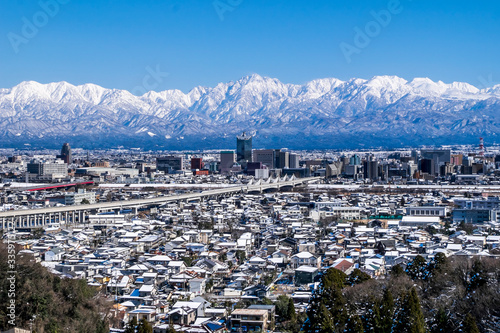 呉羽山展望台から新幹線車両と北アルプス望む雪景色の富山市街地パノラマ