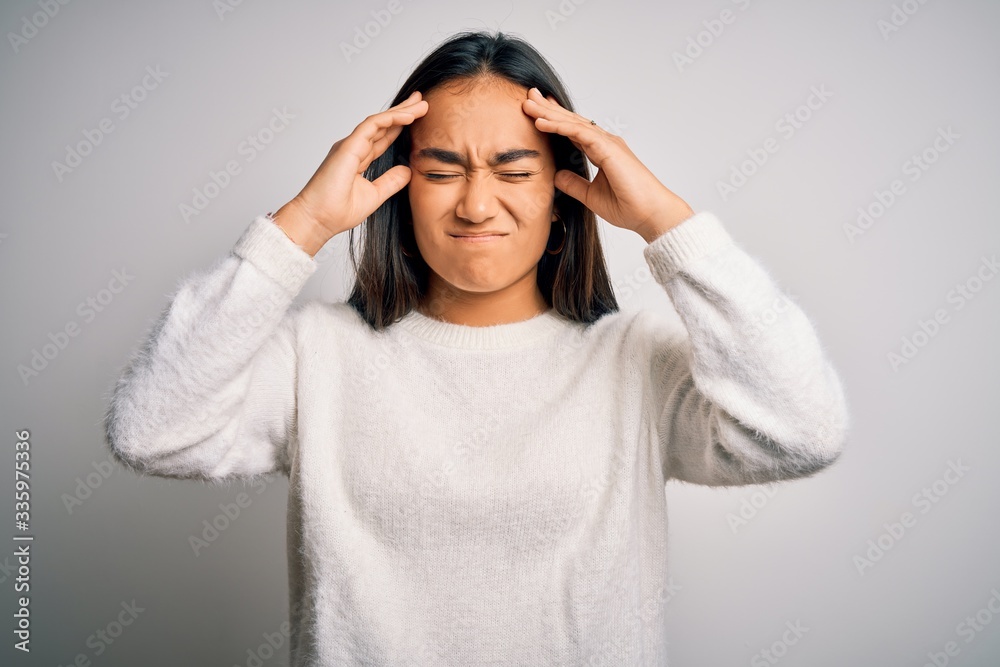 Young beautiful asian woman wearing casual sweater standing over white background suffering from headache desperate and stressed because pain and migraine. Hands on head. Young beautiful asian woman wearing casual sweater standing over white background suffering from headache desperate and stressed because pain and migraine. Hands on head.