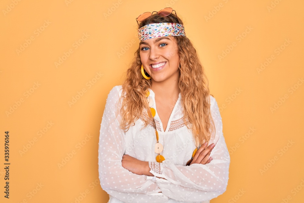 Naklejka premium Young beautiful blonde hippie woman with blue eyes wearing sunglasses and accessories happy face smiling with crossed arms looking at the camera. Positive person.