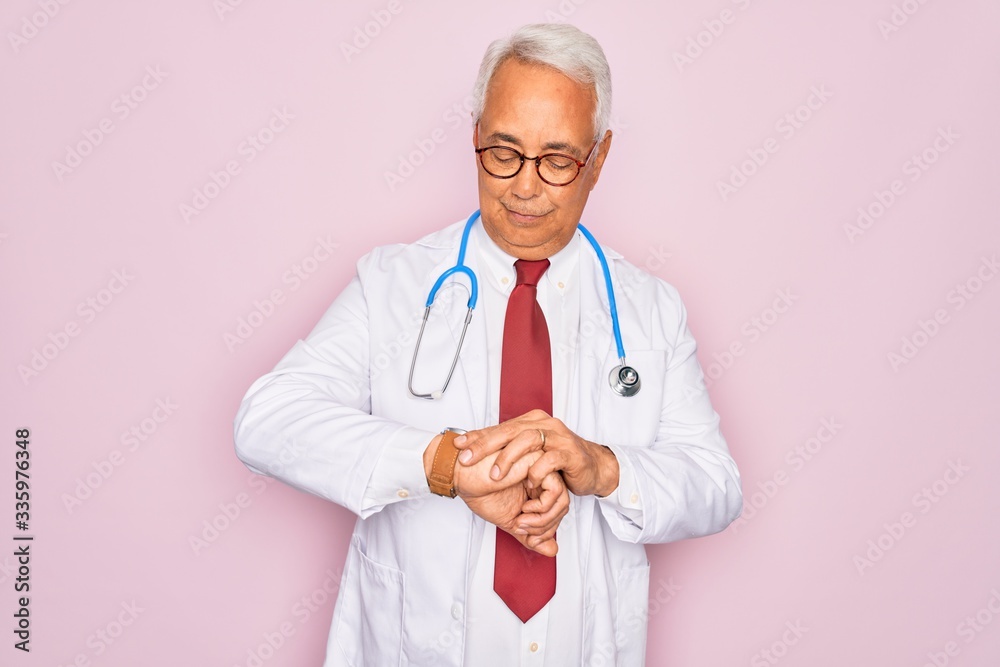 Middle age senior grey-haired doctor man wearing stethoscope and professional medical coat Checking the time on wrist watch, relaxed and confident Middle age senior grey-haired doctor man wearing stethoscope and professional medical coat Checking the time on wrist watch, relaxed and confident