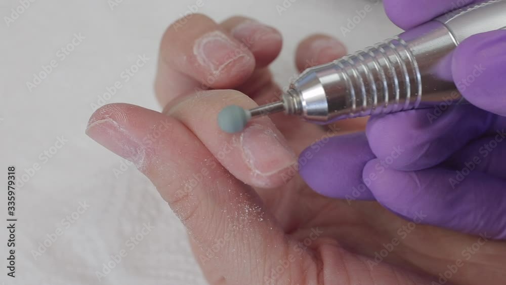 Young woman removes gel shellac polish from nails using manicure machine, close up shot Young woman removes gel shellac polish from nails using manicure machine, close up shot