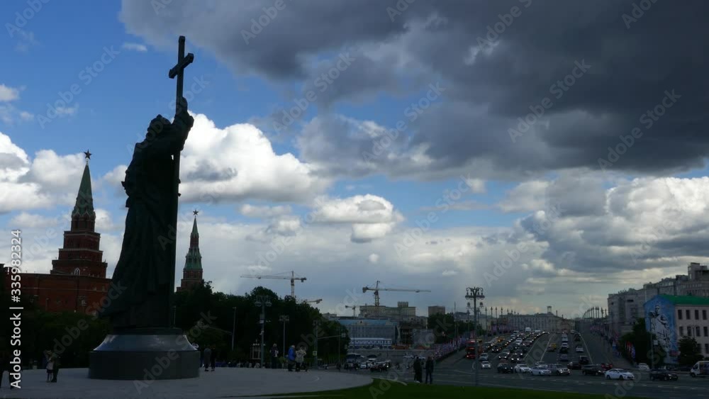 Cars moving in traffic on a bridge in Moscow city center with Monument to Prince Vladimir, Kremlin red stars and cloudy blue sky in the background Cars moving in traffic on a bridge in Moscow city center with Monument to Prince Vladimir, Kremlin red stars and cloudy blue sky in the background