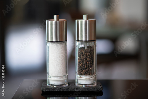 Glass and metal modern bottle contain classic ingredient salt and pepper on dinning table.
