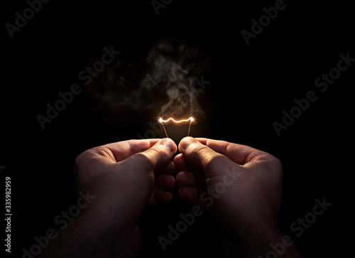 Hands holding burning lightbulb filament