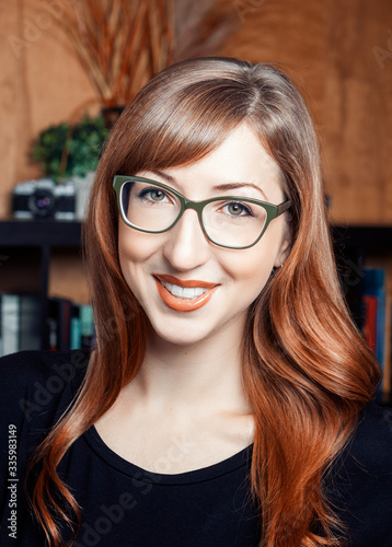 Woman with red hair and glasses smiling. 