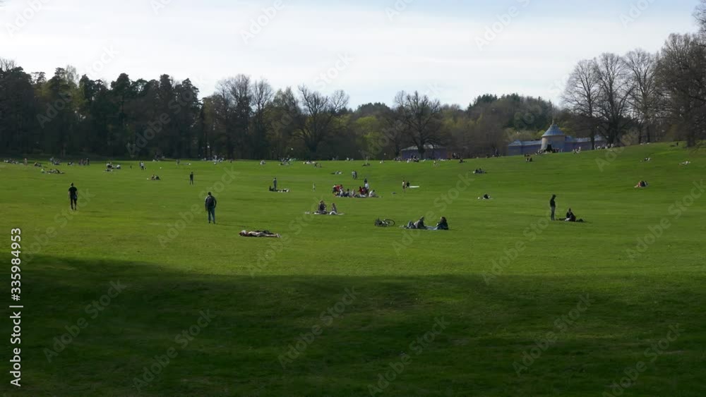 Long shot unrecognizable crowd of people enjoying summer sitting on grass in a park Long shot unrecognizable crowd of people enjoying summer sitting on grass in a park