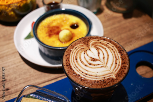 Fotografie Cafe latte with latte art on a cup with Vanilla Crème Brûlée on the background