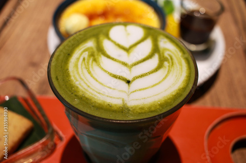 Obraz na plátně Close up image of Green matcha latte with latte art on a glass with Vanilla Crème Brûlée dessert