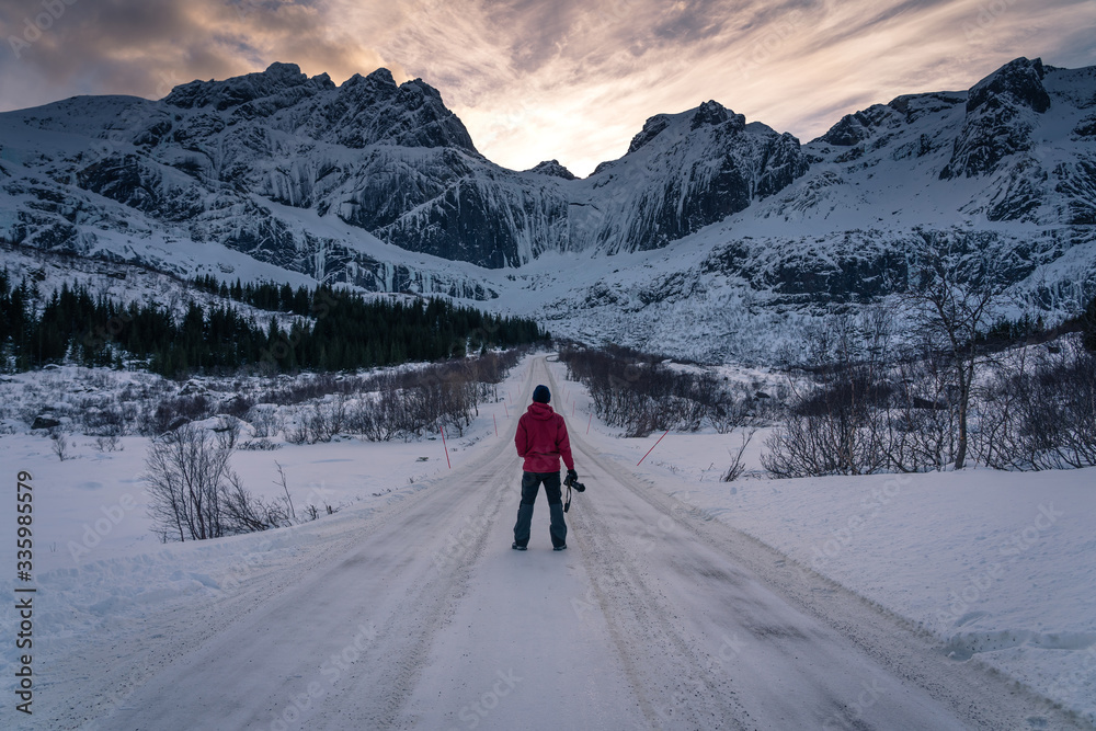 A photographer standing on road to Nusfjord in Lofoten island, Scandinavia