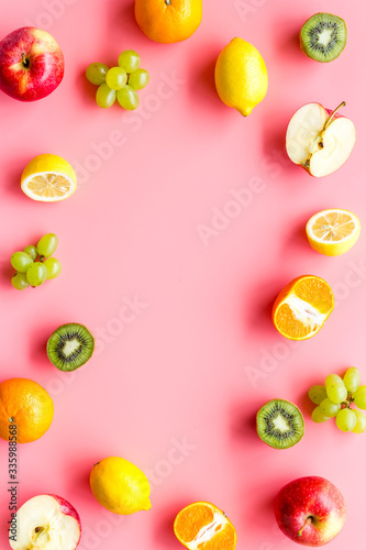 Fototapeta Naklejka Na Ścianę i Meble -  Colorful fruit mockup. Cut apple, kiwi, citrus on pink background top-down copy space