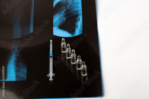 X-ray film thoracic spine with medical face mask. Concept of medical service, diagnosis and treatment. Syringe with pain medications in glass vial for scoliosis or osteochondrosis. Copy space for text photo