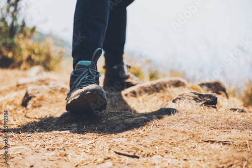 Closeup image of a woman hiking with trekking boots on the top of mountain