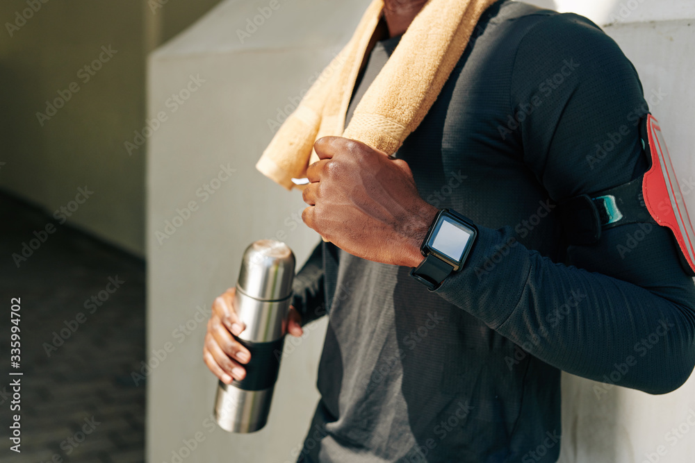 Naklejka premium Smart watch with health application on arm of sportsman standing outdoors after morning run