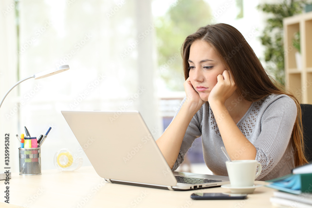 Bored entrepreneur looking at laptop screen at home Bored entrepreneur looking at laptop screen at home
