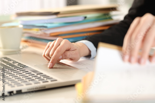 Overworked executive hands checking documents using laptop