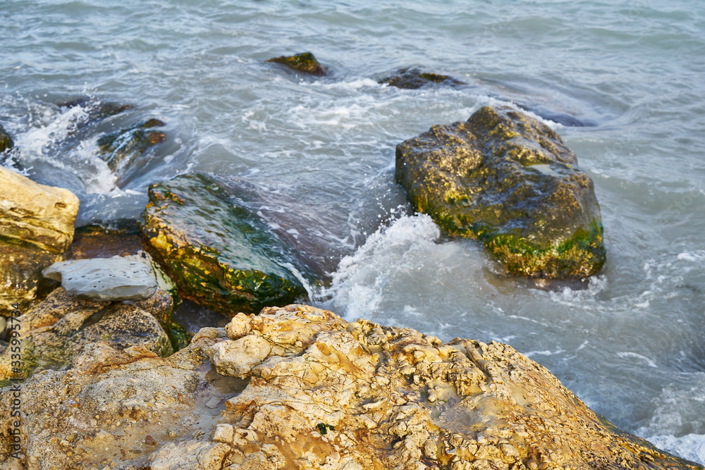 Fototapeta premium Rocky seashore. Sea waves roll over stones.