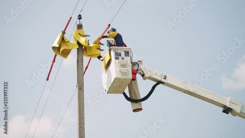 laborer puts yellow sheets onto power line cables in basket