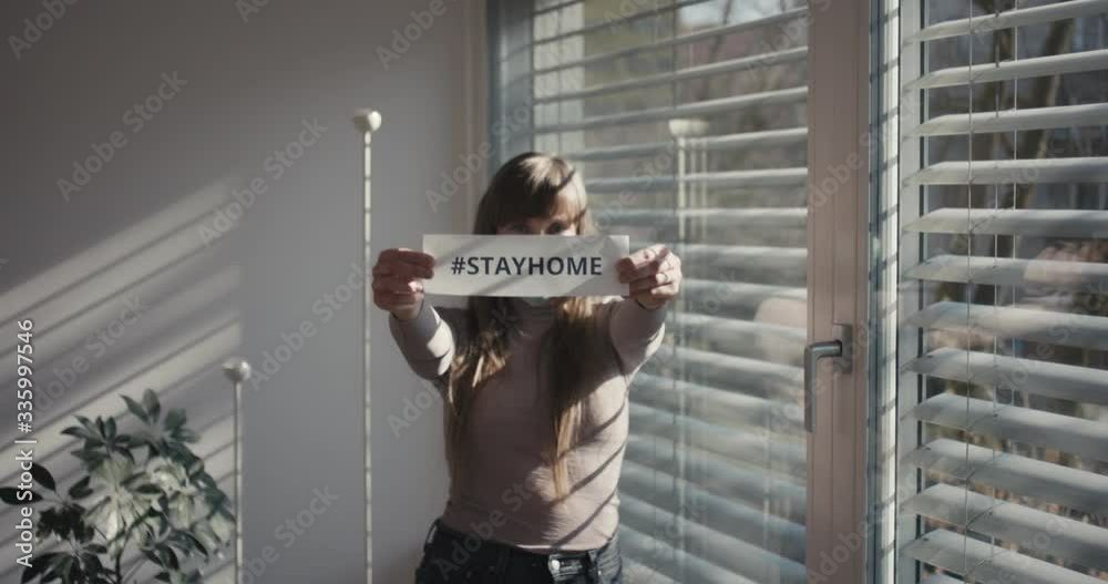 Woman with protective face mask shows stay home sign during coronavirus covid 19 pandemic outbreak social distancing self isolation in quarantine