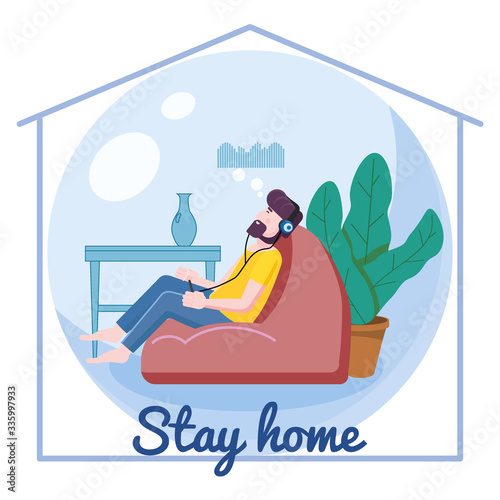 Stay home awareness quarantine consept banner self isolation.Young man sitting on a bean bag with headphones and listening to music at home