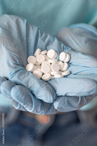 Closeup doctor or nurse hands in blue rubber gloves with handful pills