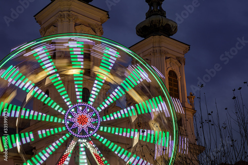 Moving ferris wheel in front of Mariahilfer Church spire, Graz, Austria