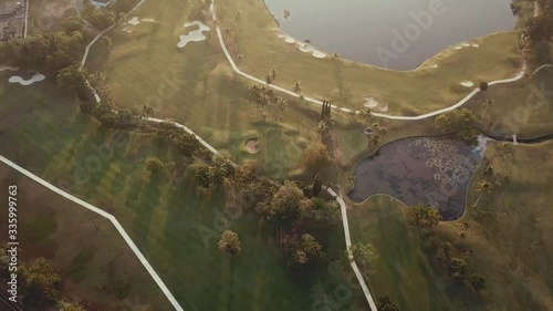 Aerial view of a golf course with a lake at sunrise