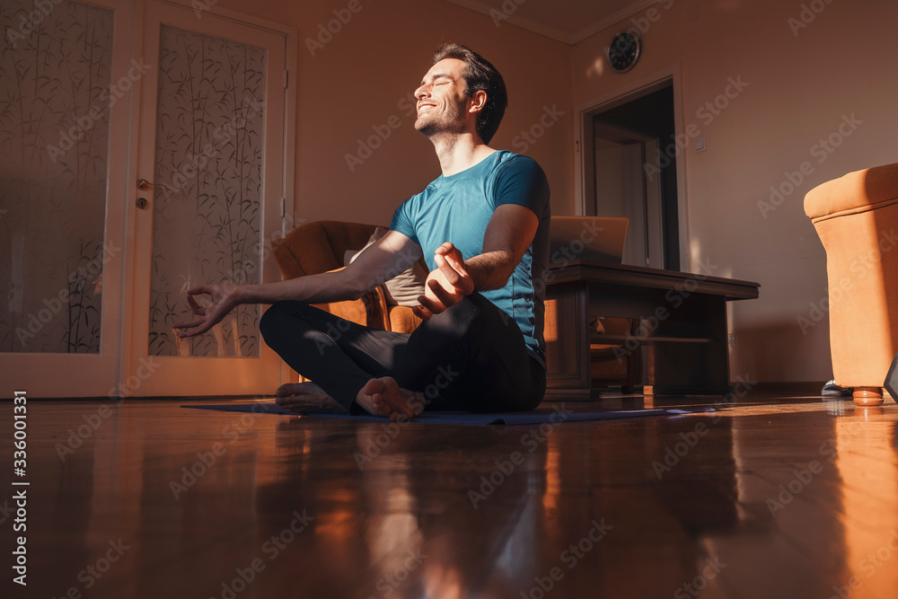 Handsome man practicing yoga in his living room, he feel peaceful and enjoying in moments