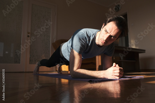 Sport, fitness and healthy lifestyle concept - man doing plank exercise at home © Teodor Lazarev