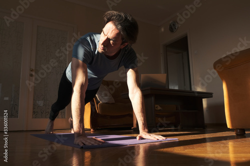 Sport, fitness and healthy lifestyle concept - man doing plank exercise at home