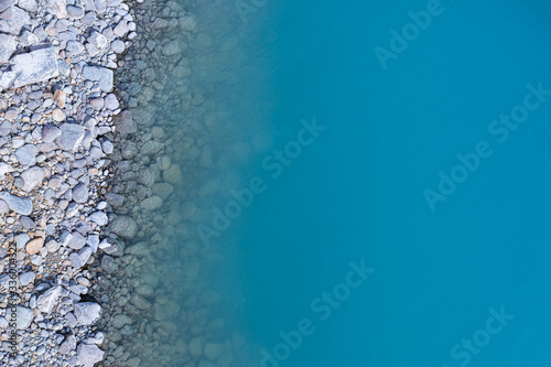 Fototapeta Naklejka Na Ścianę i Meble -  Aerial top view of turquoise lake and rocks abstract background at Tekapo, New Zealand