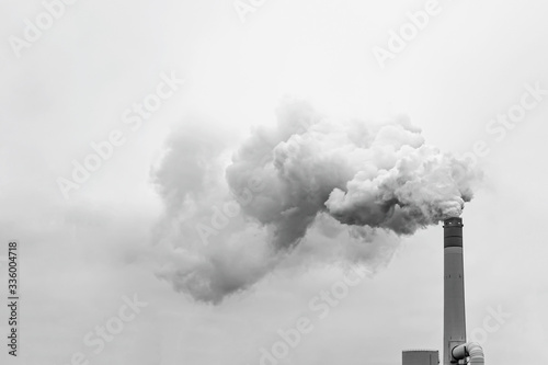 Tall chimney exhausting or pulling a huge quantity of smoke, mist or pollution in the air
