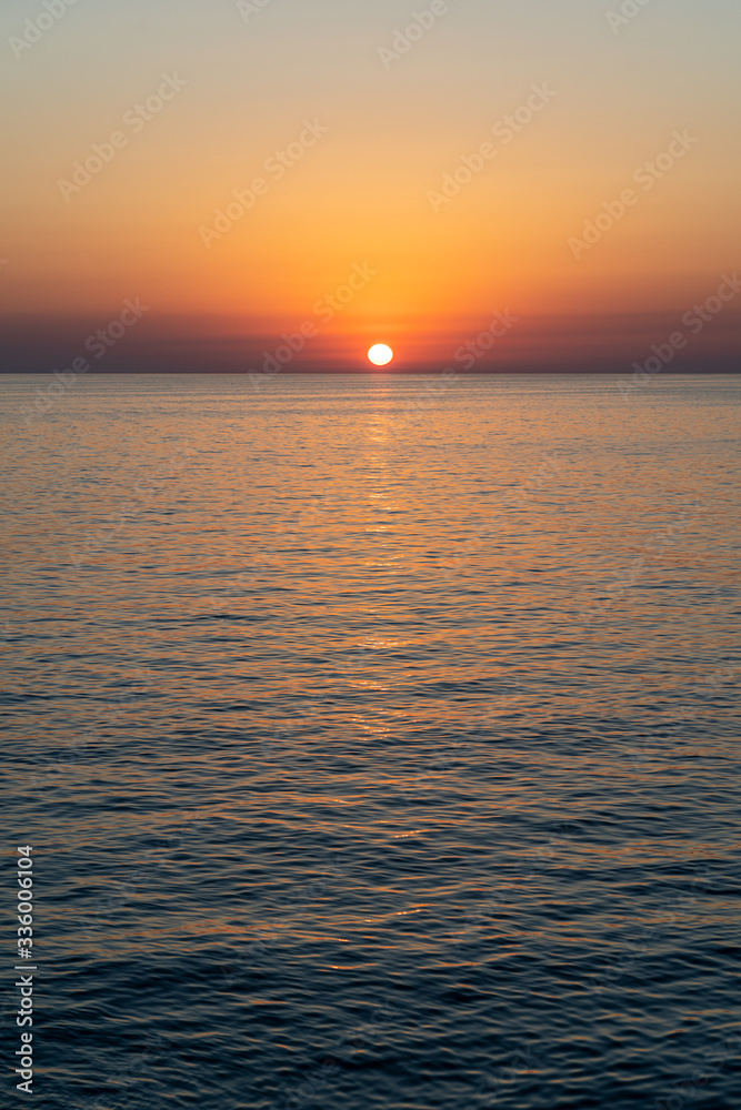 Fototapeta premium The sun is setting over the ocean